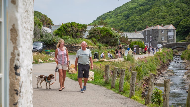 Visitors walking with a dog in Boscastle harbour, Cornwall